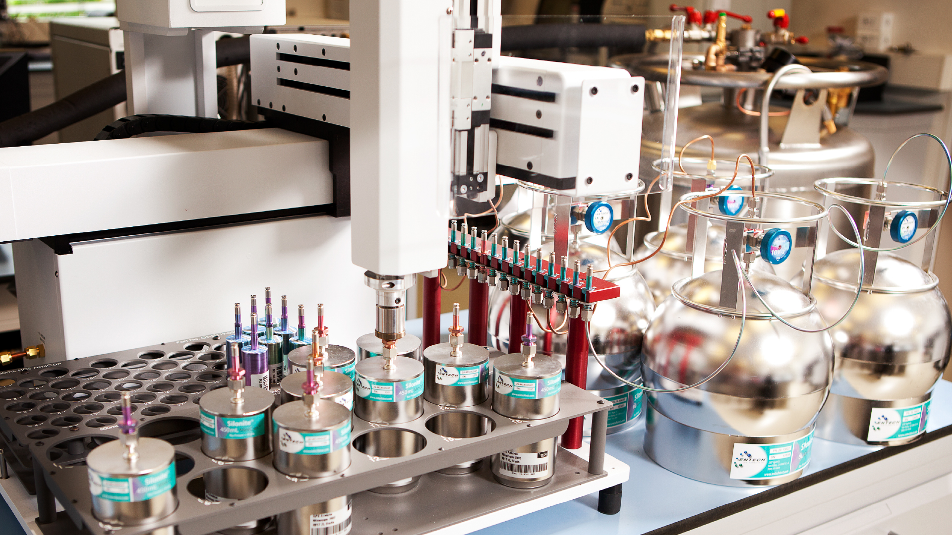 Laboratoriumopstelling met geautomatiseerde apparatuur en cilindrische containers.
