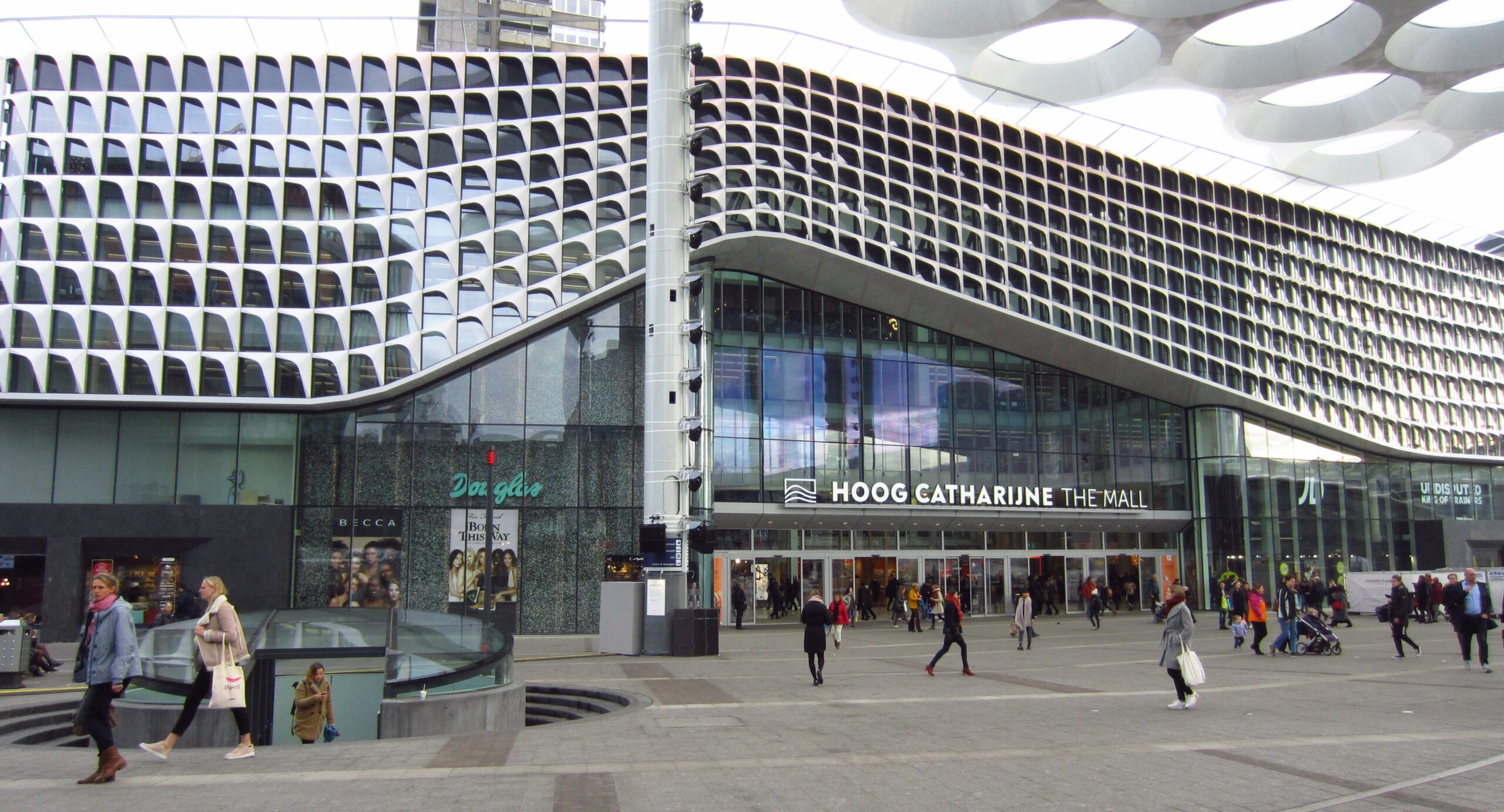 Ingang van Hoog Catharijne winkelcentrum met moderne architectuur en mensen die in- en uitlopen.